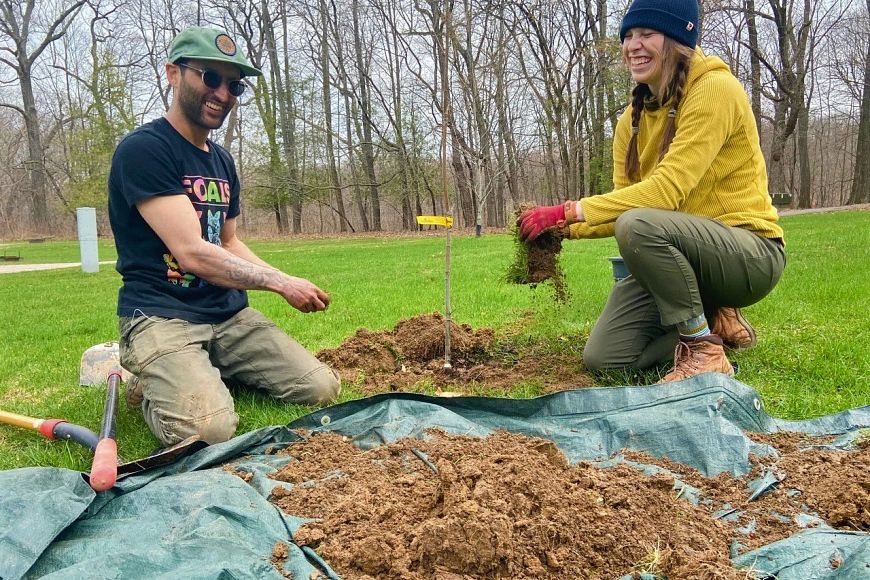Two people planting trees in the springtime.
