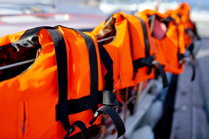 Life jackets hang on the rail of a boat.