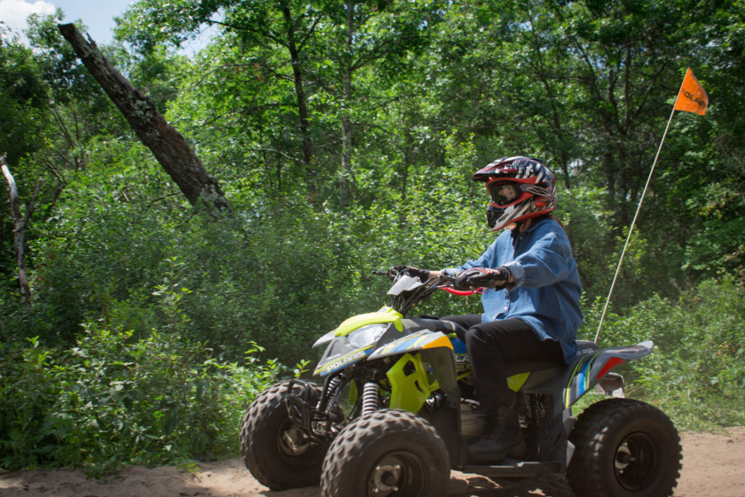 A side-profile of someone riding an ATV on a trail. 