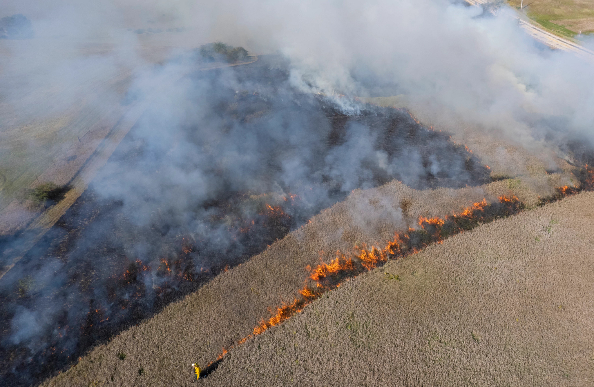 A DNR burn crew member walks along open conservation area conducting a controlled burn of sections 