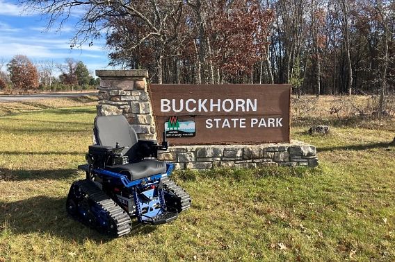 An outdoor wheelchair next to the welcome sign at Buckhorn State Park