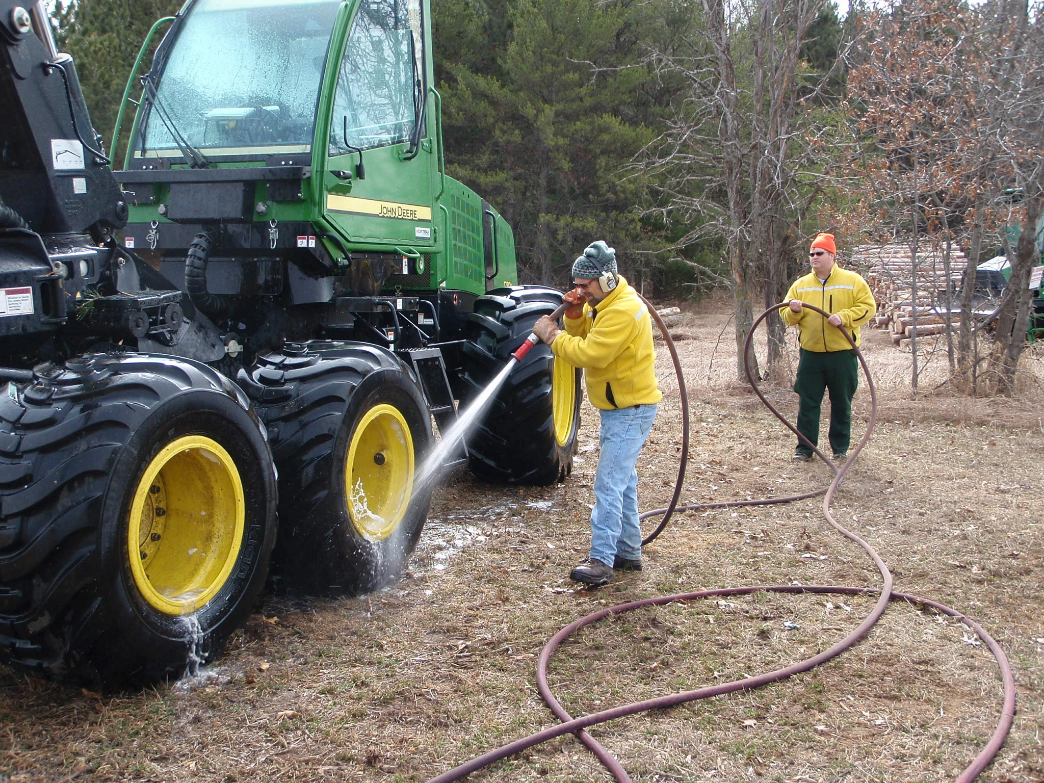 A worker hoses down the wheels of a vehicle after a workday in the woods. 