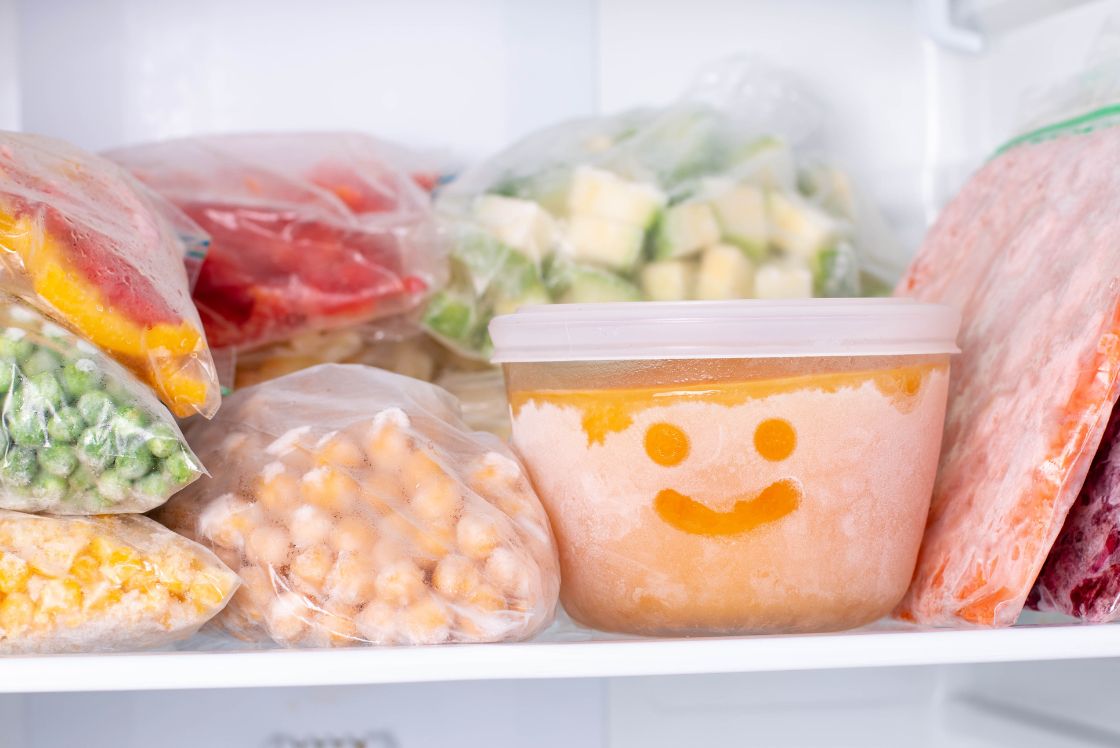 Frozen food in bags and containers in a freezer.