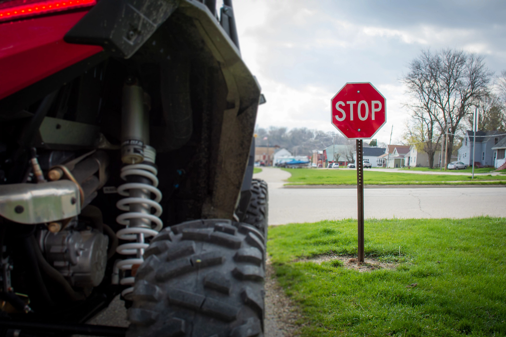 close-up of wheel of red atv stopped at stop sign on a public road
