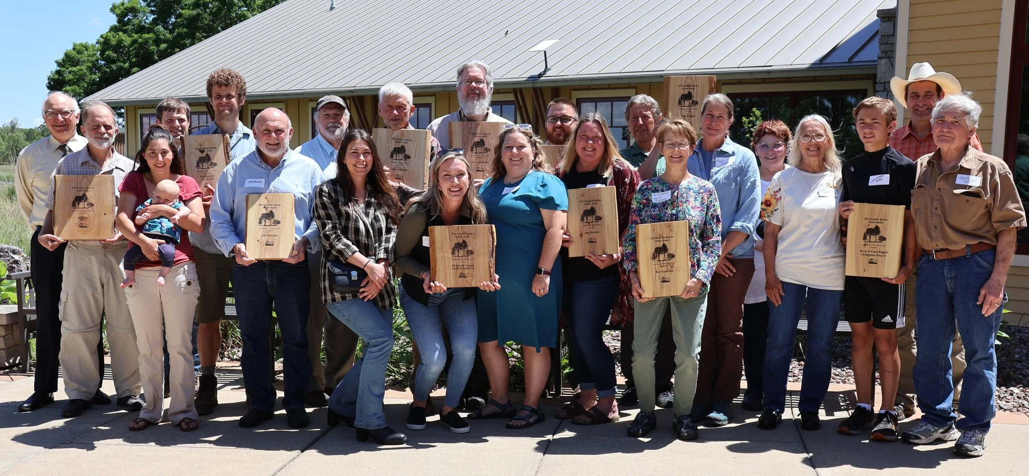 Award receipients smile while holding their plaques outside the Necedah National Wildlife Refuge.