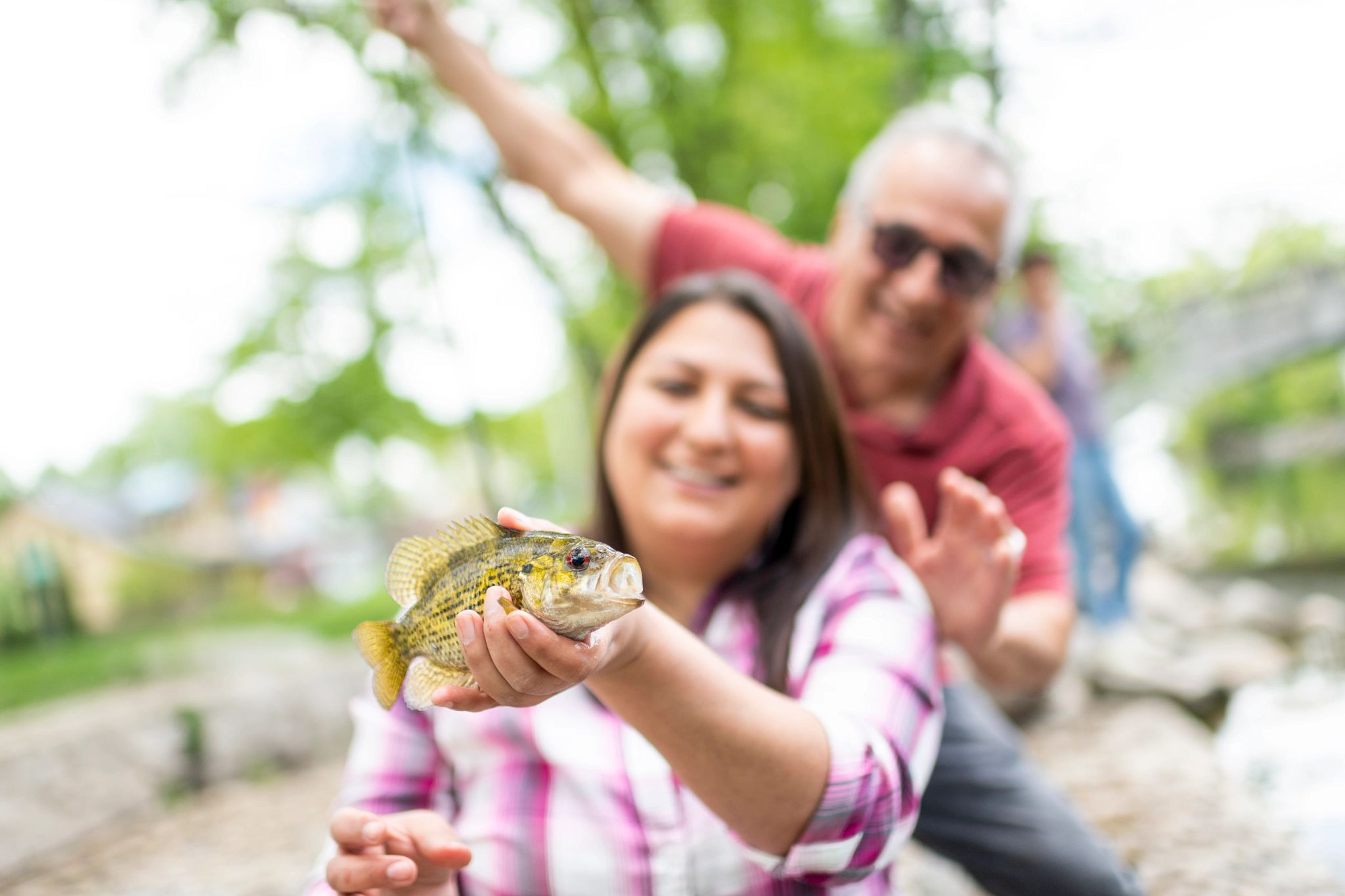 A close up of a small fish, a woman in smiling in the background