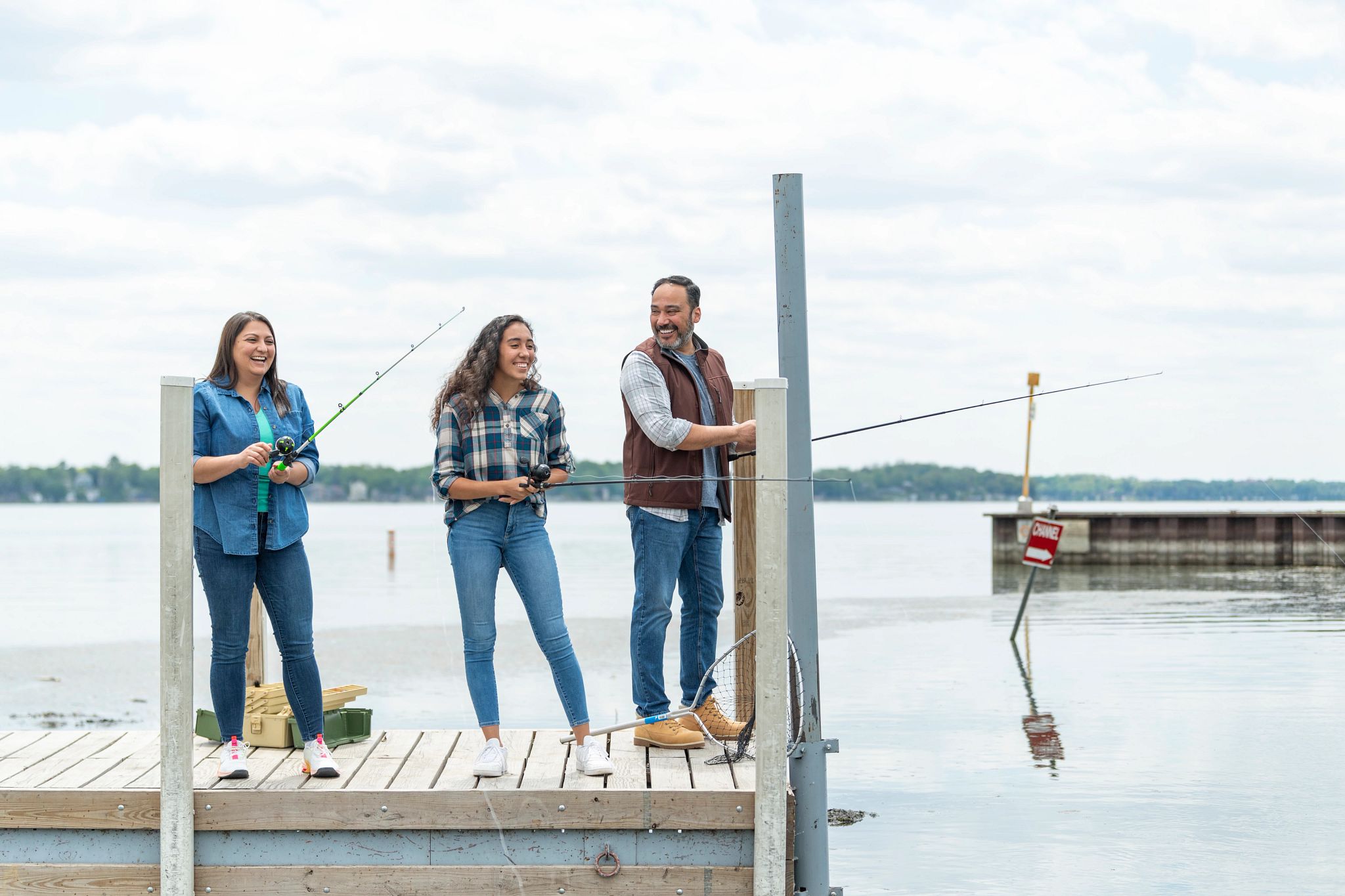 three people fishing on a pier