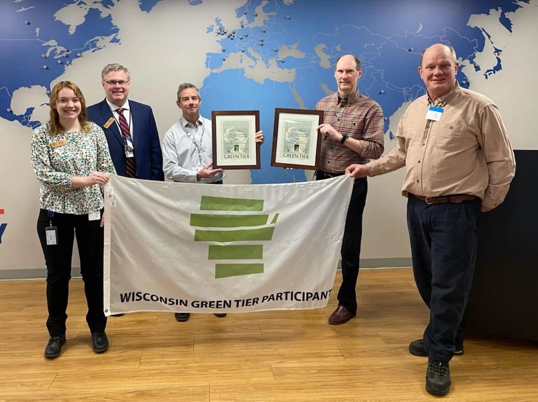 An image of DNR holding a Green Tier Banner with Brady USA employees, a company recently accepted as participants.