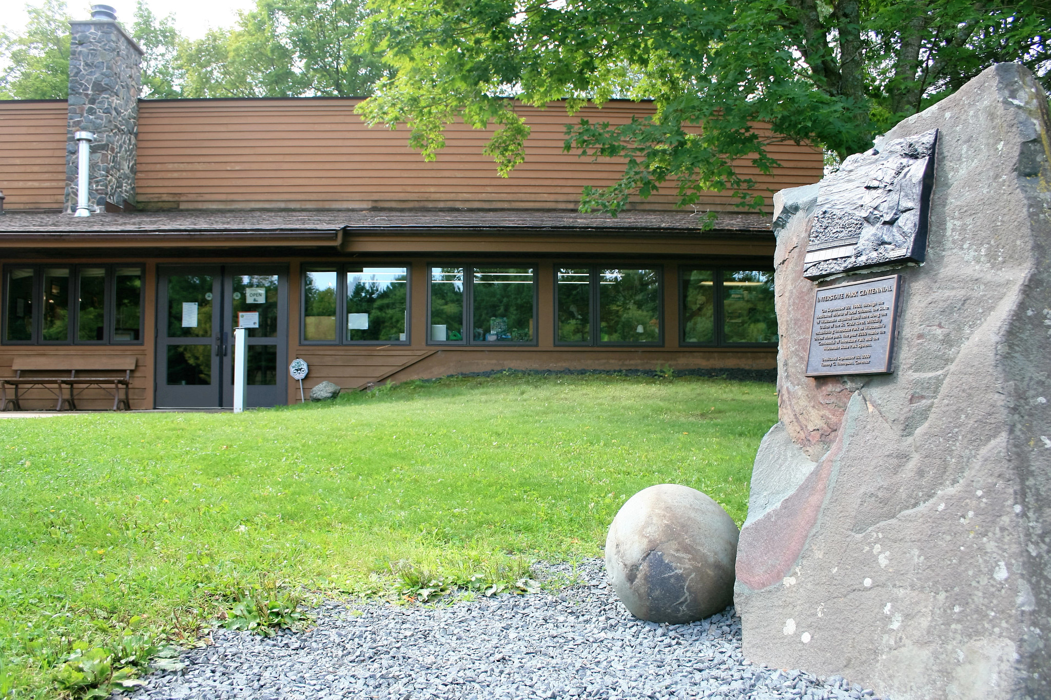 ice age interpretive center exterior with green grass and rock with plaque in forground.