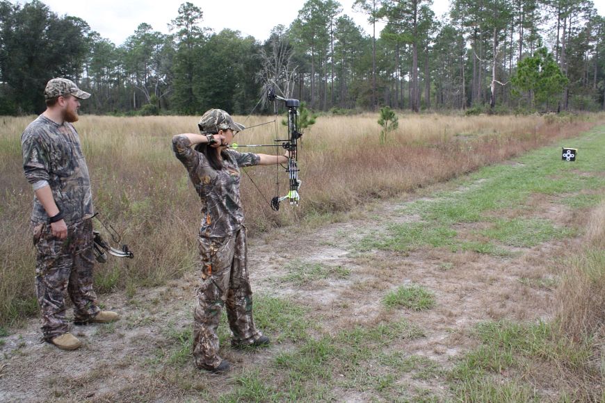 a youth hunter with an older male in camouflage clothes using a crossbow