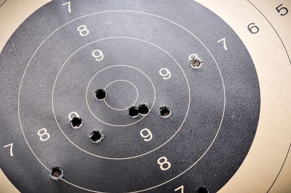 A closeup of a black and tan shooting range target, with bullet holes in the middle.