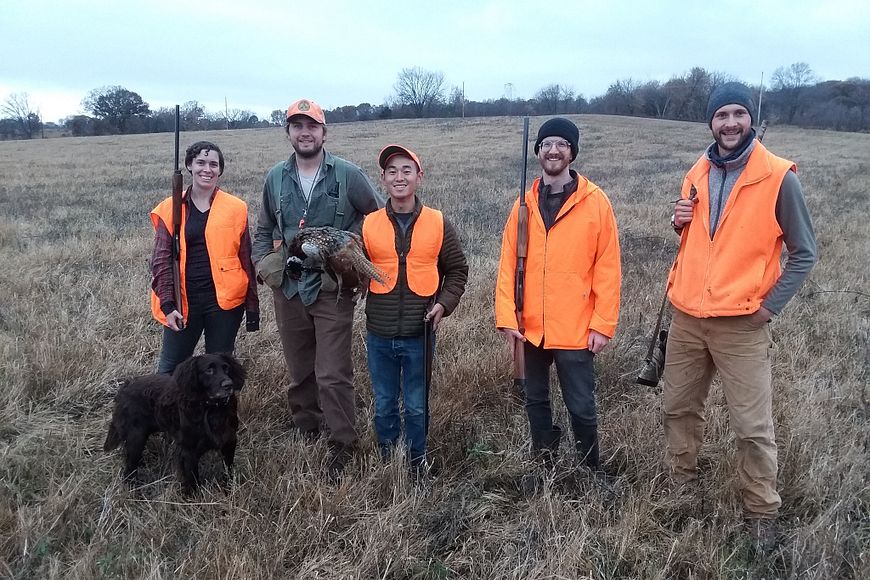 A group of four hunters in a field.