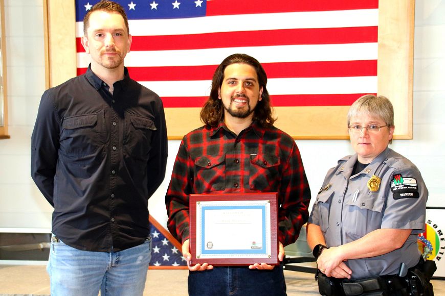 Mark Moersch Jr., the 2021 recipient of the DNR Ethical Hunter Award, standing with his award with Ryan Muckenhirn, sales representative at Vortex Optics Inc. on his right and DNR Capt. April Dombrowski on his left.