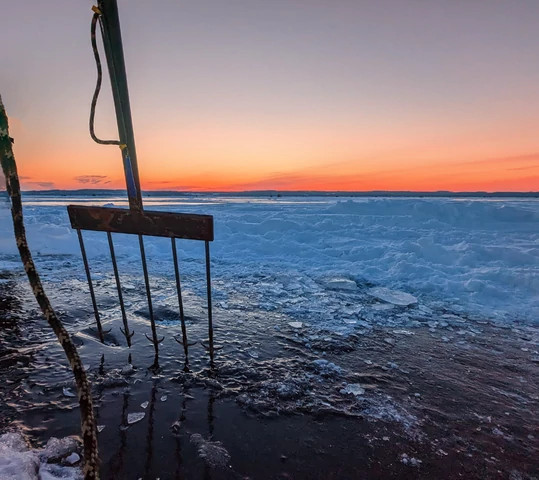 spear stuck in ice against sunrise in background