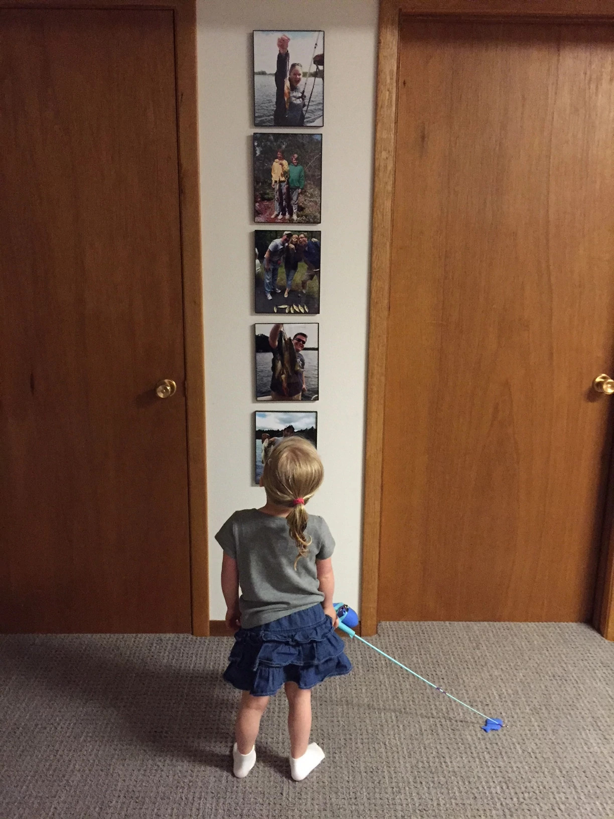 young girl holding fishing rod and looking at photos of people fishing