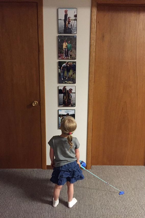 young girl holding fishing rod and looking at photos of people fishing