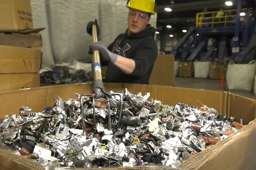 worker using rake to push e-cycling parts